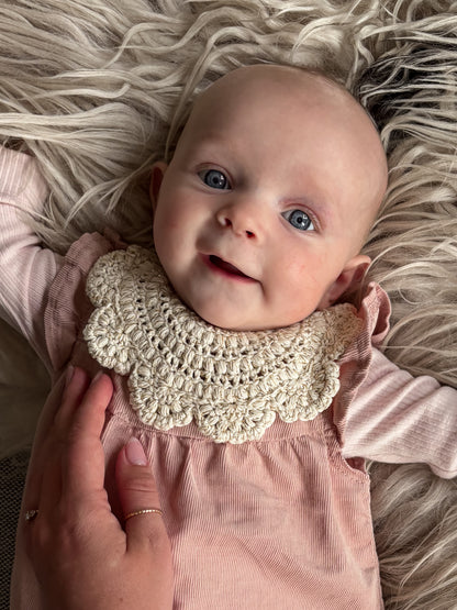 Baby med hæklet savlesmæk i blomstermønster